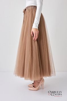 A mesmerizing elegance of flares and volumes, the Aria Taupe Tulle Maxi Skirt takes the art of fashion to a new level, combining grace and poise with a hint of playfulness. The Aria Taupe Tulle Maxi Skirt is a dream in tulle. Crafted from exquisite, high-quality tulle fabric, it drapes and flows beautifully, creating an enchanting visual effect. The long-lined design extends gracefully to the floor, giving you a dramatic and elegant silhouette. Featuring a thin, unobtrusive elastic band at the w Full Tulle Skirt, Tulle Maxi Skirt, Chic Blouses, Brown Skirts, Satin Blouse, Chiffon Skirt, Tulle Fabric, Unique Designers, Designer Collection