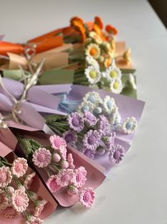 a bunch of paper flowers sitting on top of a white table next to each other