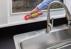 a person holding a spray bottle near a kitchen sink