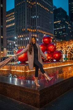 a woman is posing in front of a fountain