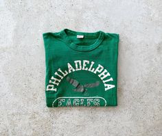 "Philadelphia Eagles t-shirt in good vintage condition. Size tag marked size S but would fit modern day women's size x-small best. Please refer to all photos for wear. Length: 21\", shoulder to hem Width: 14\", pit to pit (Measured flat) A note on vintage t-shirt sizing: To ensure a perfect fit, we recommend measuring your favorite t-shirt and comparing it to the measurements specified above for this item. PLEASE READ BEFORE PURCHASE: All of our items are pre-loved vintage and may show signs of Philadelphia Eagles T Shirt, Raglan Pullover, Philadelphia Eagles, Vintage Tshirts, Size Tag, Eagles, Pennsylvania, Philadelphia, Top Shirt