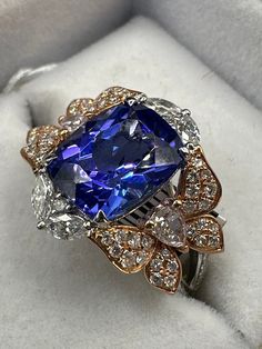 5.10-carat Tanzanite Cushion & 1.14 ctw Diamonds, 18k 2 Tone Gold 4.70 grams ring size 9.25 Four-prong set rectangular cushion modified mixed cut natural Tanzanite, measuring 11.00 x 9.00 x 6.54mm (depth est).  approx. weight of 5.10ct. Clarity is eye clean, medium, strong, violet-blue color, (GIA vB 5/5), cut is good.  Four, two-prong set marquise-shaped cut diamonds, measuring 4.50 x 2.20 x 1.39mm (depth est), 4.00% GTCF approx. total weight of 4 stones=0.34ct. Color F-G, Clarity VS-2 Two, three-prong set pear-shaped cut diamonds, measuring 4.00 x 3.00 x1.89mm (depth est), 4.00% GTCF approx. total weight of 2 stones=0.28ct. Color G, Clarity VS-2 Forty-eight, four split top prong set round brilliant cut diamonds, measuring 1.40 - 1.20 x 0.78mm (depth est), 4.00 GTCF approx. total weight o Luxury Cushion Cut Topaz Ring With Accent Stones, Luxury Cushion Cut Tanzanite Jewelry, Rectangular Cushion, Character Board, Natural Tanzanite, Multi Stone Ring, Multi Stone, Round Brilliant Cut Diamond, Cushion Cut