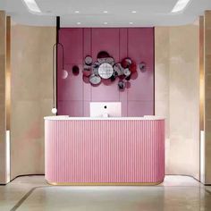 a pink and gold reception desk in a hotel lobby with circular mirrors on the wall