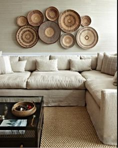 a living room filled with furniture and lots of plates hanging on the wall above it