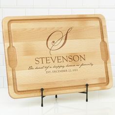 a personalized cutting board with the initials and date engraved on it, stands against a white tile wall