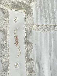 a white shirt with buttons and lace on it