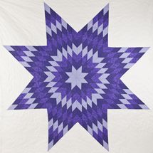 a purple and white quilt with a star design on the center, in front of a white wall