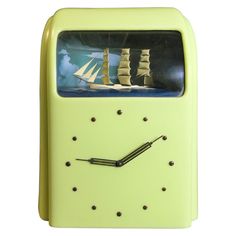 a yellow clock with a sailboat on the front and side of it's face