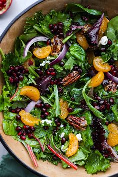 a salad with oranges, cranberries and pecans in a wooden bowl