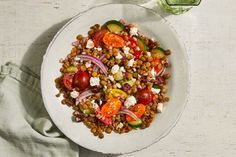 a white bowl filled with beans, tomatoes and cucumbers