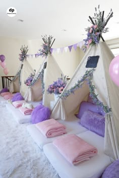 a row of teepee tents sitting on top of a bed covered in pink and purple blankets