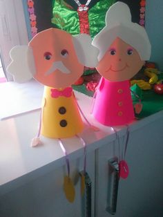 two paper dolls sitting on top of a counter next to each other in front of a window