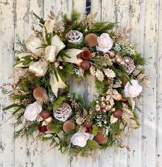 a christmas wreath hanging on the side of a white wooden wall with pine cones and flowers