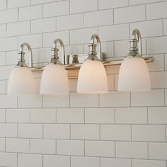 three light bathroom fixture with white glass shades on brick wall in residential home interior area