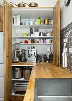 a kitchen with wooden counters and shelves filled with pots, pans and other items