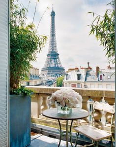 a table and chairs on a balcony with the eiffel tower in the background