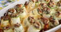 a casserole dish with zucchini wrapped in cheese and other toppings