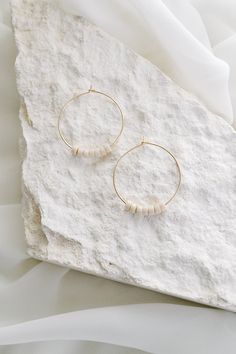 Inspired by the ebbs and flows of life, the Riverstone Collection embodies the beauty of each season we journey through. Created with beads sourced from limestone found in riverbeds, these pieces help us stay connected to the enduring peace and power of water. Product Details: 30mm gold-filled hoop earrings 7 riverstone beads on each hoop Made in Fort Collins, CO Minimalist Everyday Hoop Earrings With Natural Stones, Everyday Minimalist Hoop Earrings With Natural Stones, Minimalist Beach Jewelry With Heishi Beads, Small Hoop Earrings With Natural Stones For Everyday, Everyday Small Hoop Earrings With Natural Stones, Everyday Natural-toned Round Bead Jewelry, White Earthy Everyday Jewelry, Earthy Everyday White Jewelry, Minimalist Small Hoop Beaded Jewelry