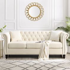 a living room with white furniture and a large mirror on the wall