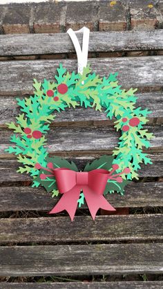 a paper wreath on a wooden bench with a red bow hanging from it's side