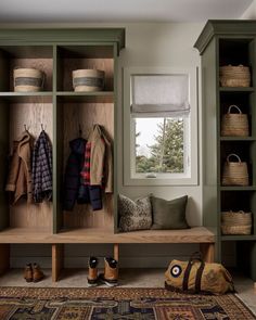 a wooden bench sitting under a window next to a shelf filled with coats and shoes