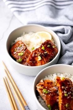 two bowls filled with meat and rice next to chopsticks on a white surface