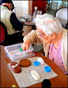 an elderly woman is making cupcakes at the table