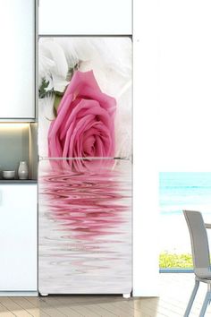 a pink rose sitting on top of a table next to a white refrigerator freezer