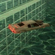 a car is floating in the water next to a tall building that has glass walls