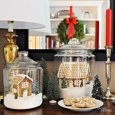 gingerbreads and cookies are on the table in front of glass jars with houses inside