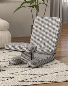 a black and white chair sitting on top of a rug next to a potted plant