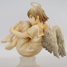 an angel figurine holding a baby in it's arms on a white surface