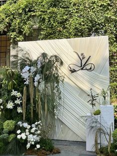 an outdoor area with white flowers and greenery on the wall, including large plants