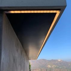 the side of a building with a view of mountains in the distance and lights on it