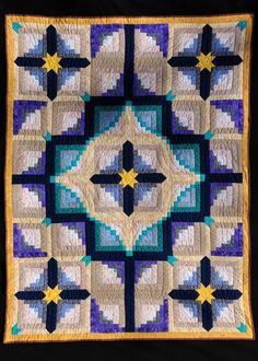 a blue and white quilt with stars in the center on a black wall hanging from a wooden frame