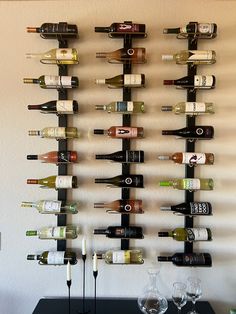 a wall mounted wine rack filled with bottles and glasses on top of a black table