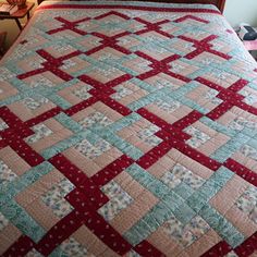 a bed with a red and blue quilt on it