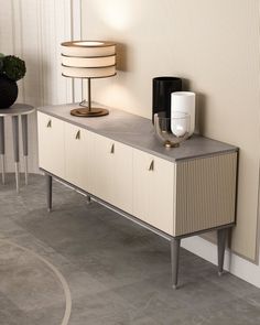 a lamp is sitting on top of a dresser next to a table with two lamps