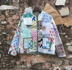 an old jacket hanging on the side of a stone wall with colorful patches and designs