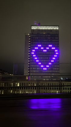 a large building with a purple heart on it's side in the city at night