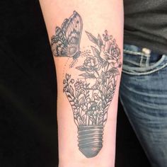 a woman with a butterfly on her arm and flowers in a lightbulb tattoo