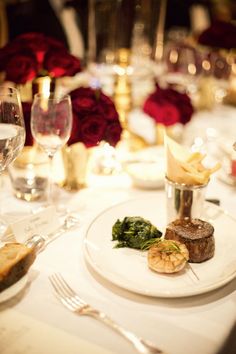 a white plate topped with food on top of a table next to wine glasses and silverware