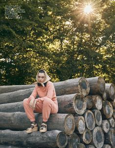 a woman sitting on top of a pile of logs