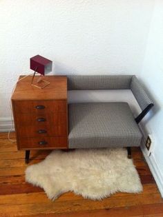 a chair with a lamp on top of it next to a dresser and rug in a room