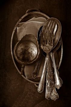 silverware and utensils are arranged in a bowl on top of a table