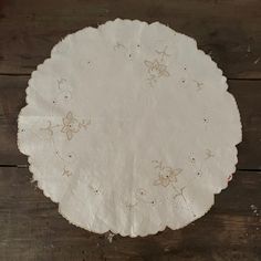 a paper doily with flowers on it sitting on a wooden table next to scissors