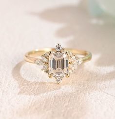 an engagement ring with a large diamond surrounded by smaller diamonds on a white cloth background