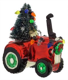 a christmas tree sitting on top of a red toy car with lights and decorations around it