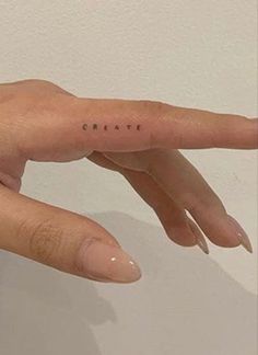 a woman's hand with the word create tattooed on her thumb and index finger