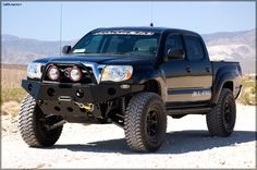 a black truck parked on top of a dirt field